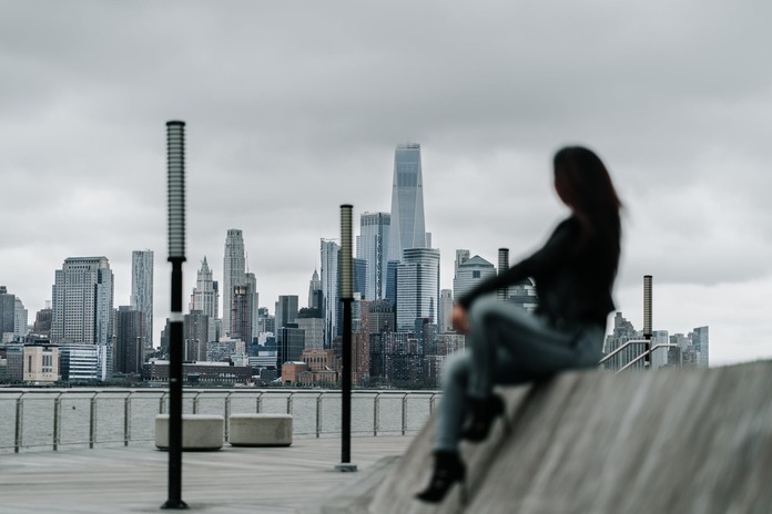 a woman looking at the city buildings near a river