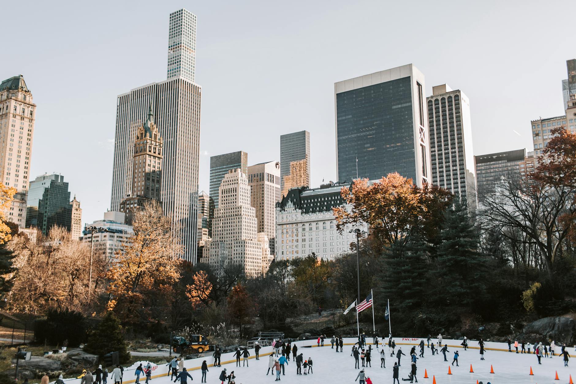people ice skating in the park near high rise buildings