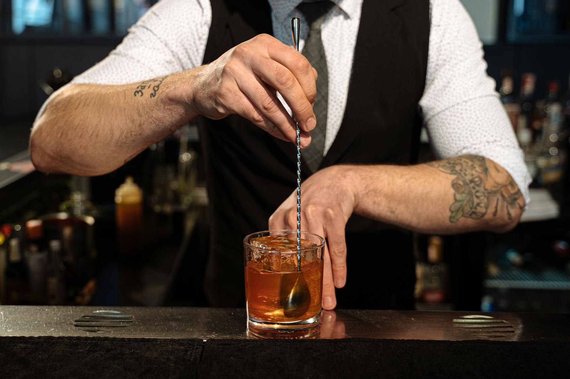 barman in black vest making cocktail